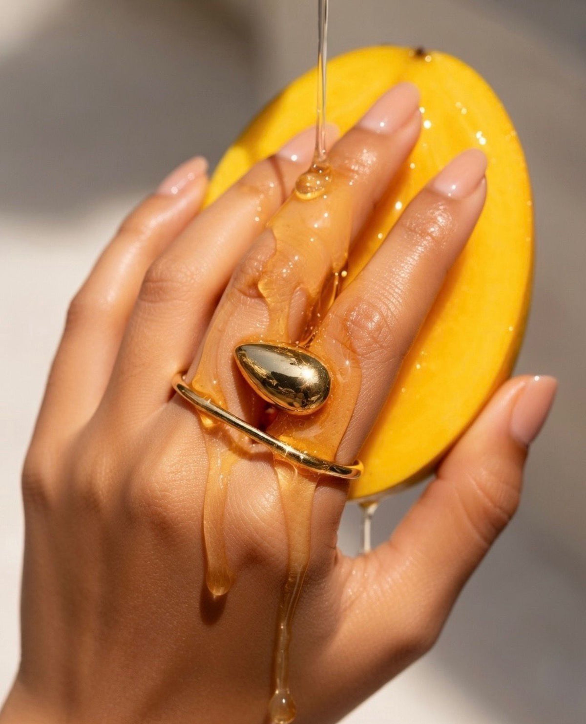 Gold teardrop ring worn on a hand