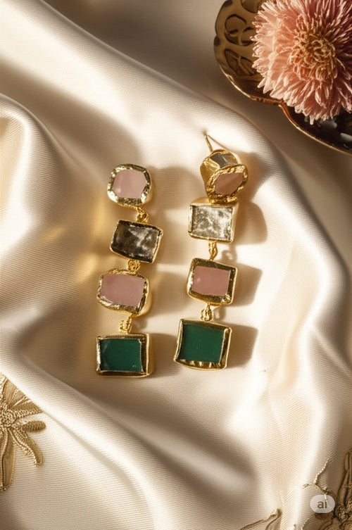 Brass earrings with colorful gemstones on a satin surface