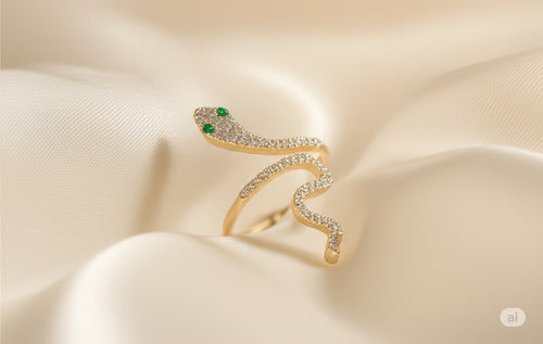 Gold snake-shaped earring with green gemstones on a beige fabric background